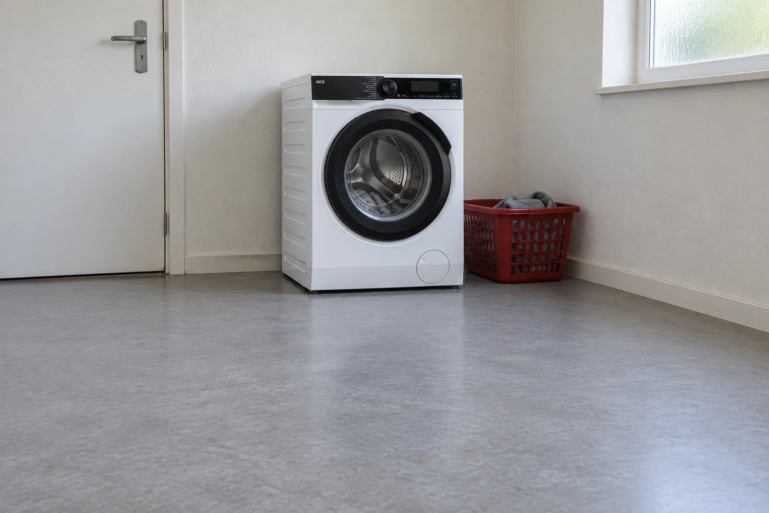 AEG wasmachine in een gewone washoek met een wasmand naast de machine.
