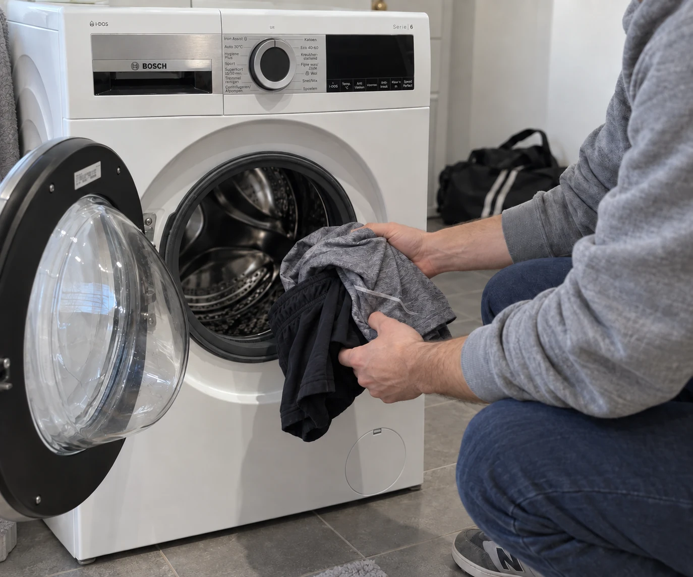 Iemand legt een kleine lading sportkleding in een Bosch-wasmachine
