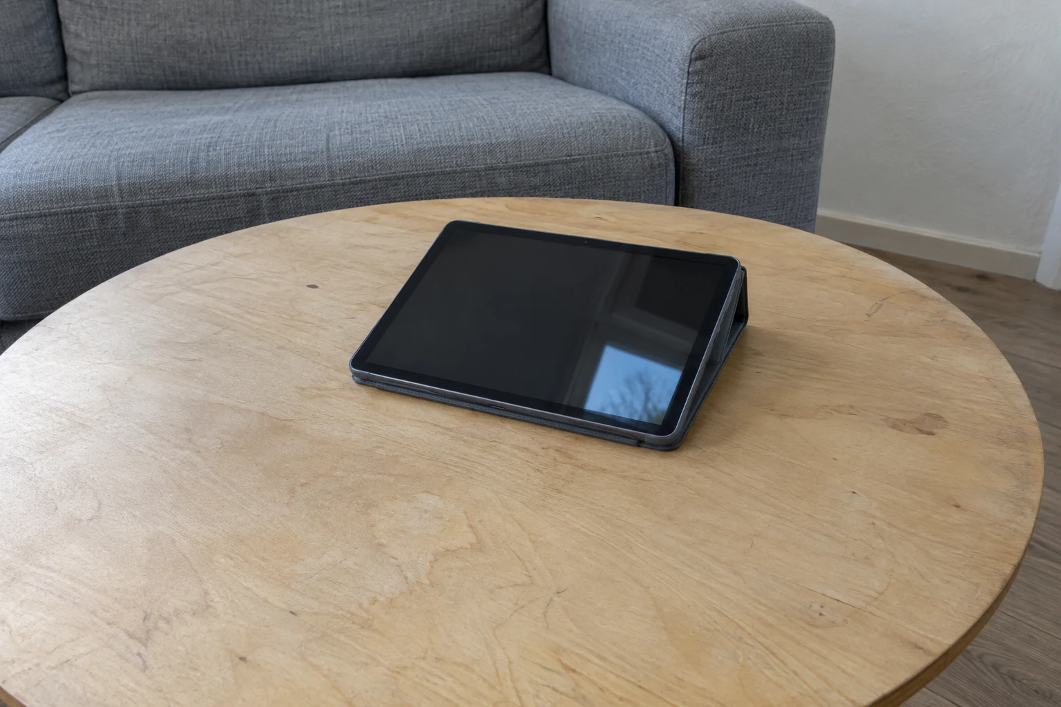 Tablet met uitgeschakeld scherm in een hoes op een lichte salontafel.