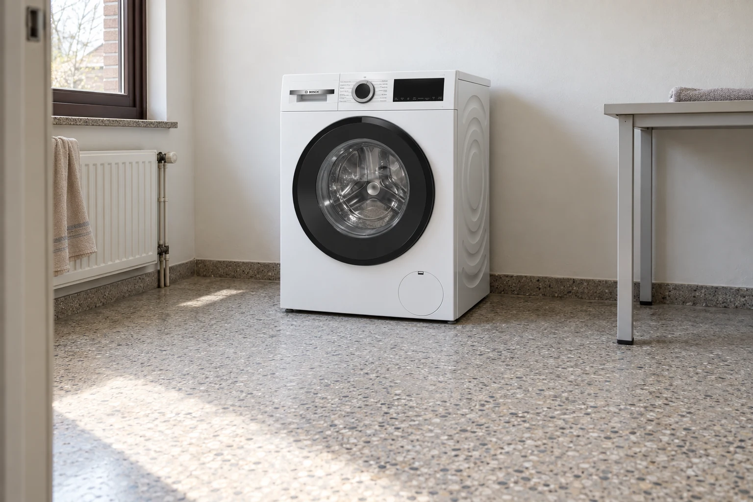 Witte wasmachine in een gewone washoek bij een raam.