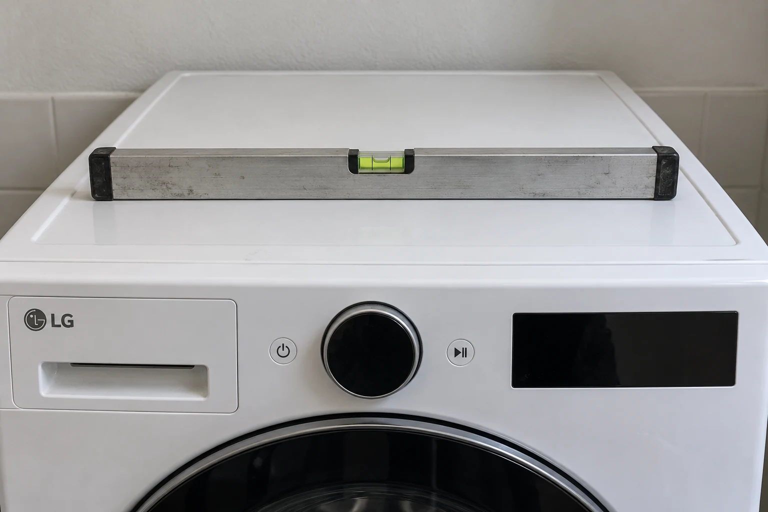 Een korte waterpas ligt op het bovenblad van een LG-wasmachine
