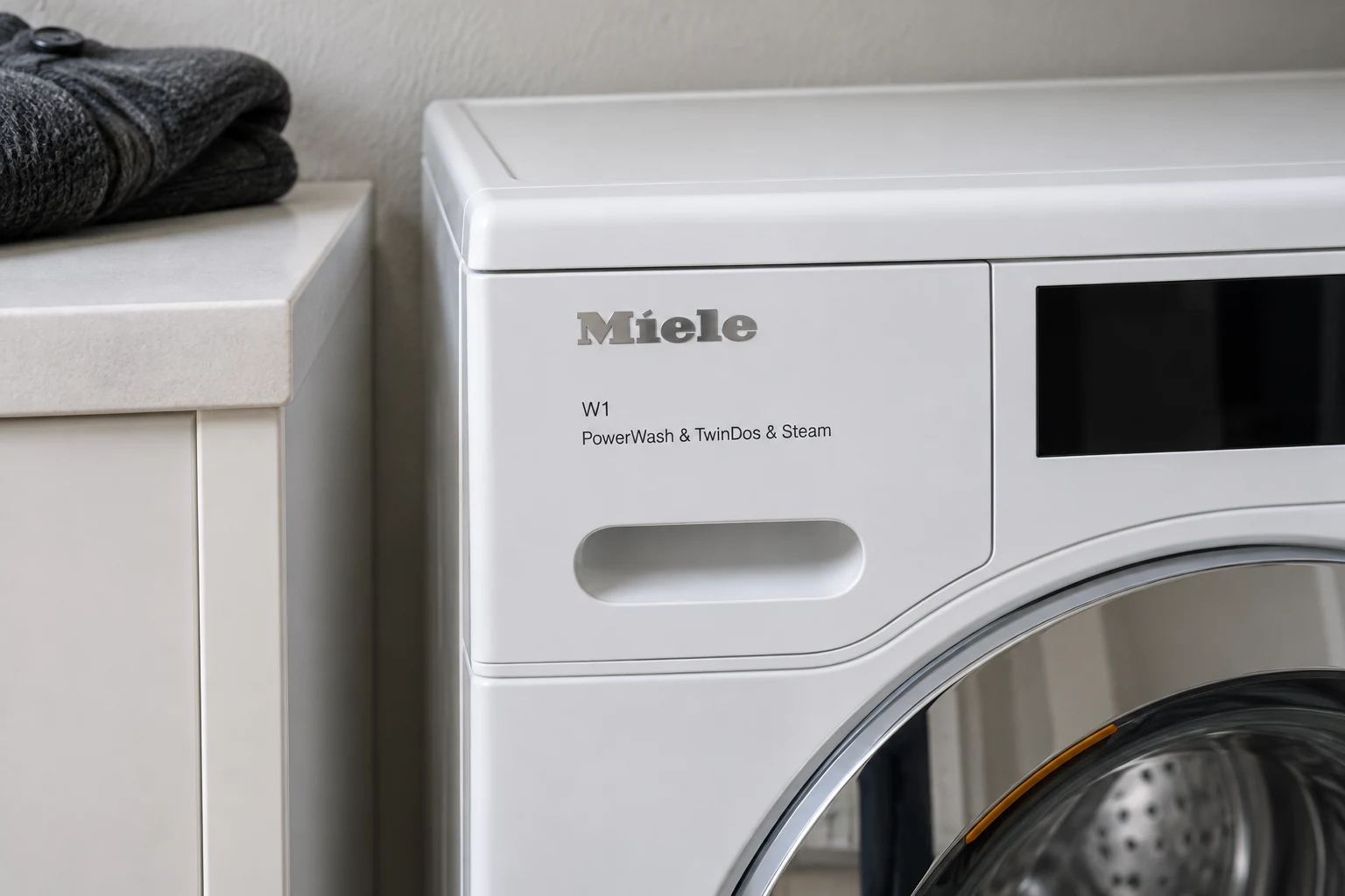 Bovenste wasmiddellade van de Miele WEG 888 naast een gevouwen vest