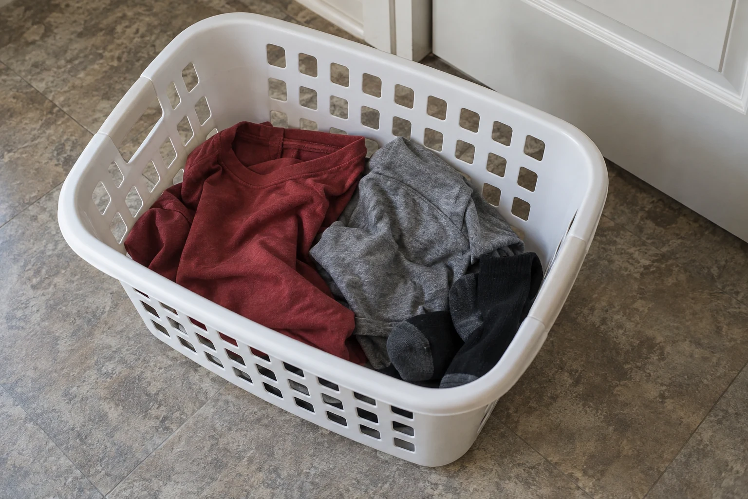 Een paar los gevouwen T-shirts en sokken in een kleine wasmand.