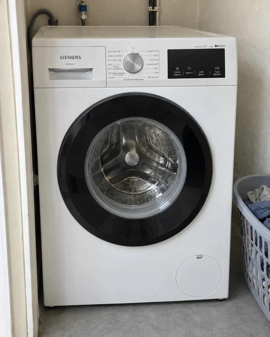Siemens WM14N07CNL in een kleine berging, met een wasmand naast de machine.