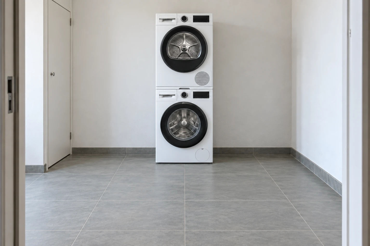 Wasmachine met droger erboven en een dun tussenstuk in een gewone bijkeuken