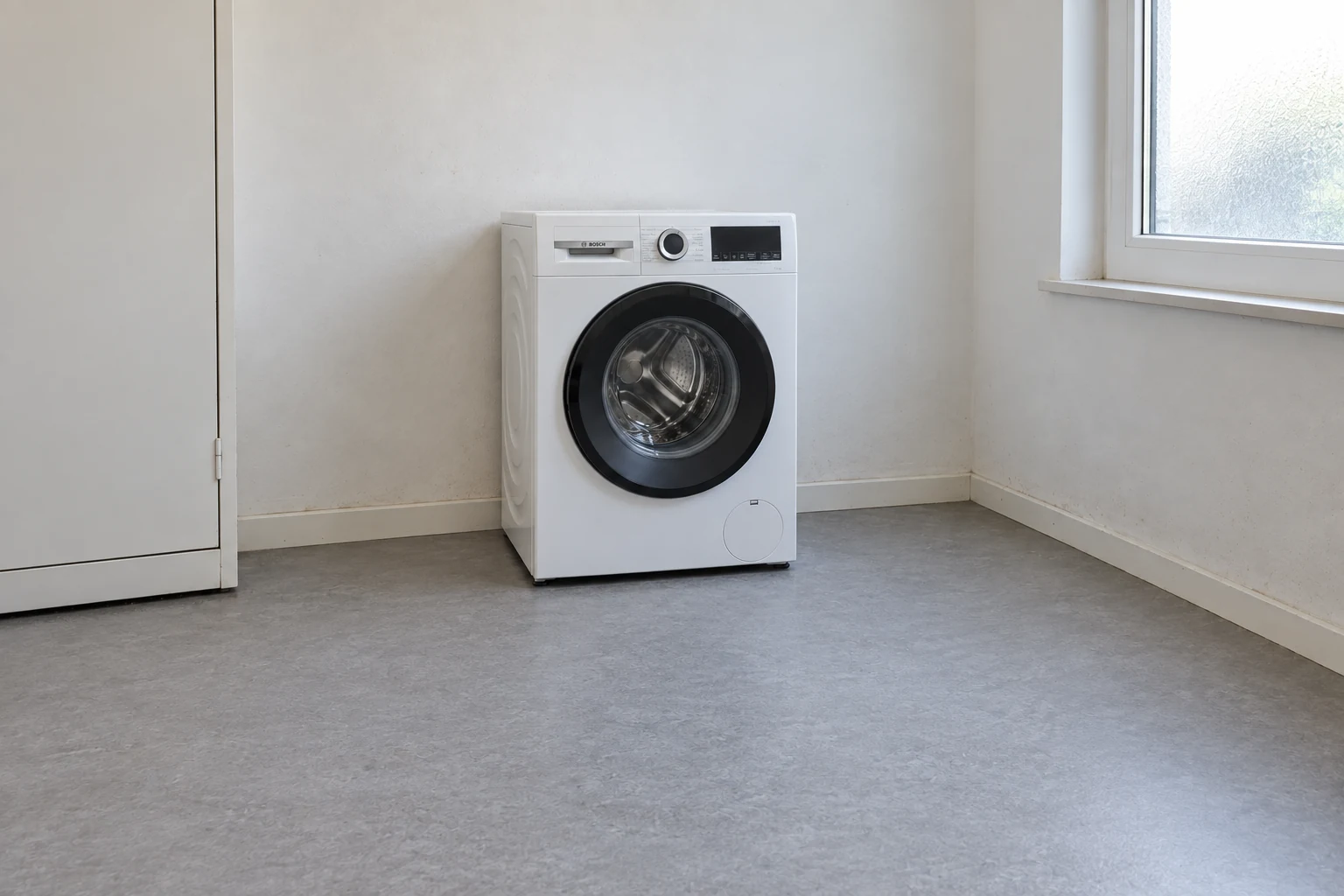 Een witte Bosch-wasmachine in een gewone wasruimte met vrije vloer ervoor.