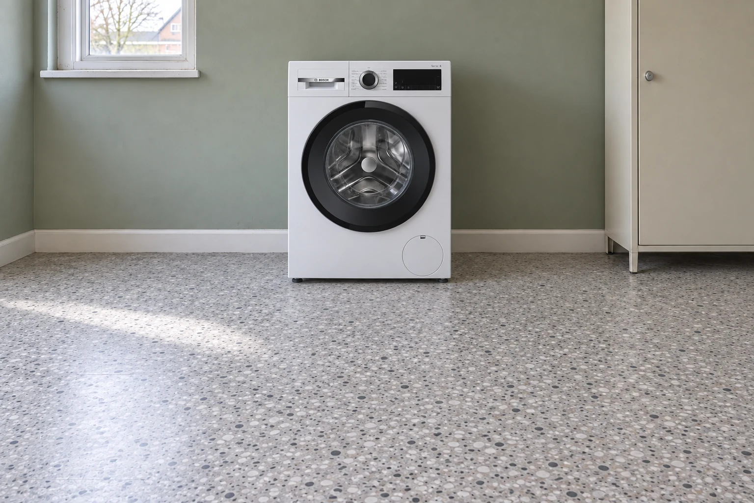 Witte wasmachine met een ronde serviceklep rechtsonder in een gewone wasruimte