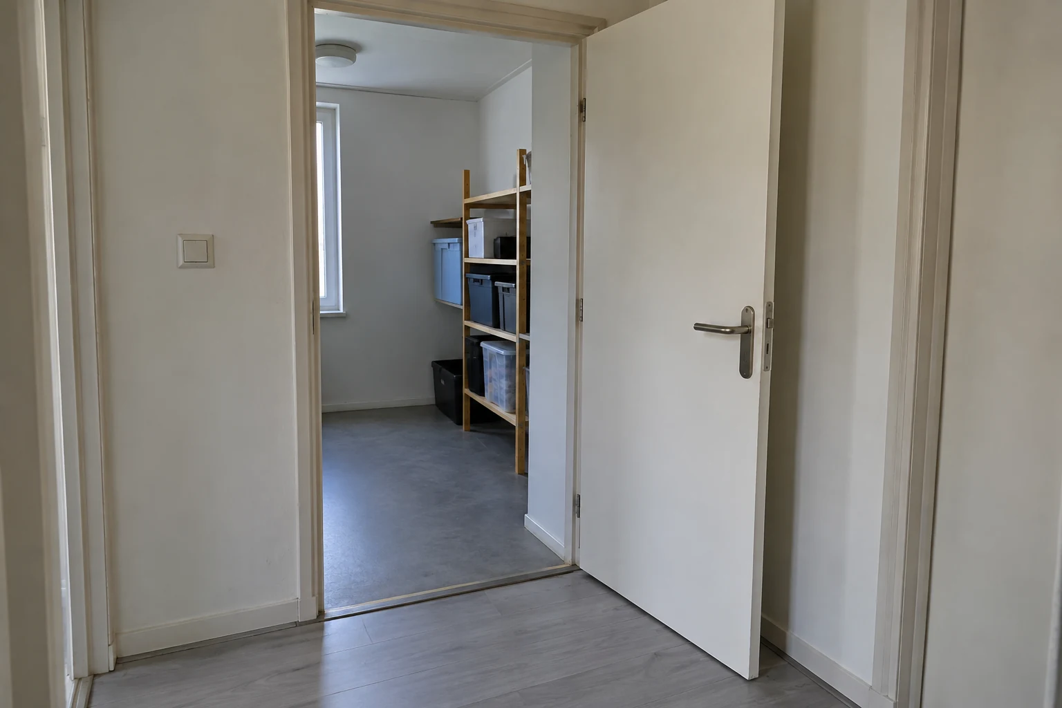 Een open binnendeur geeft toegang tot een bergruimte met een lege doorloop.