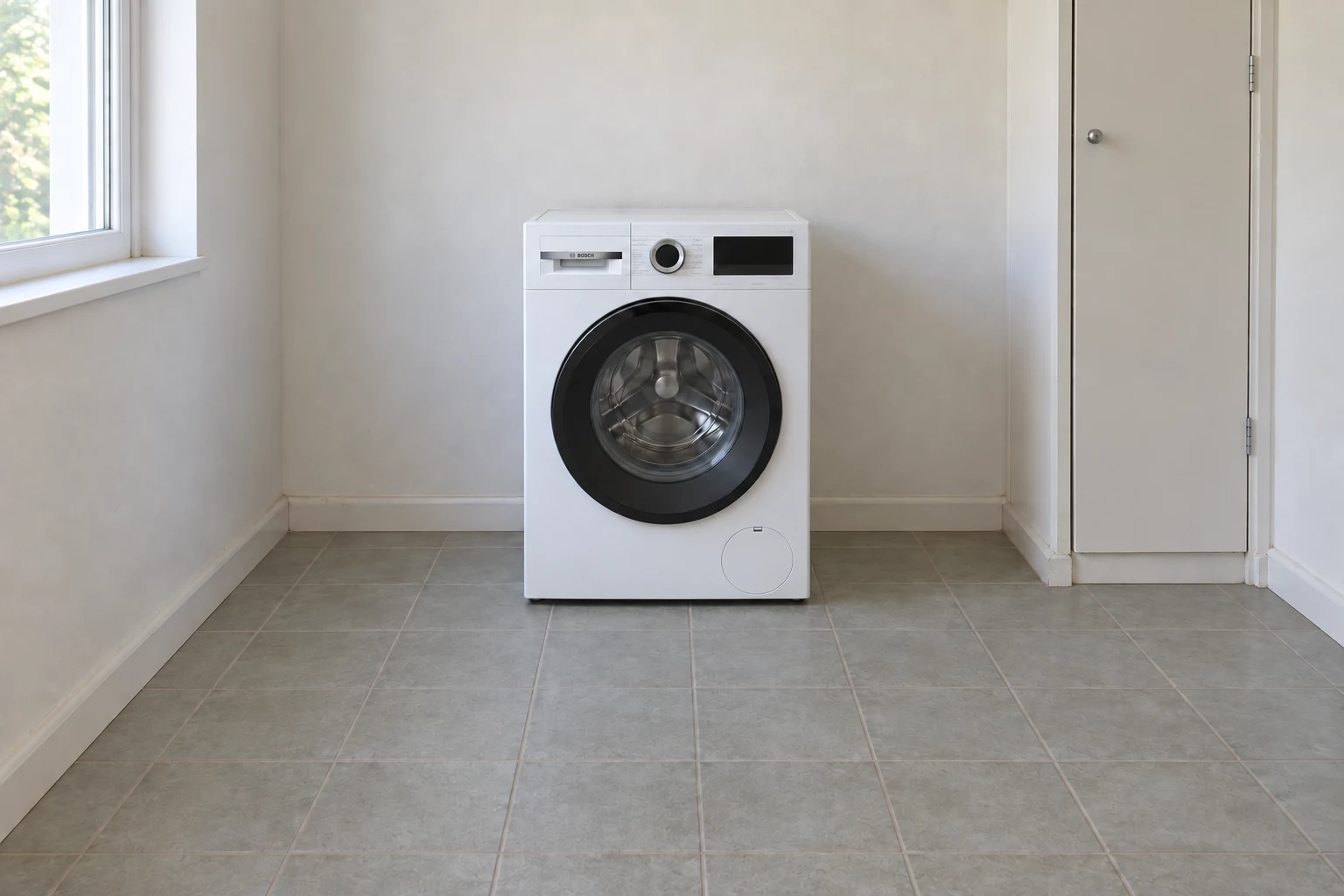 Een gebruikte witte wasmachine staat met gesloten deur in een gewone wasruimte.