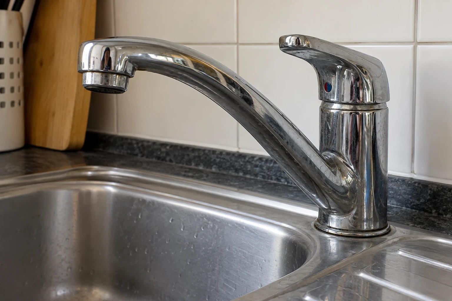 Een gewone keukenkraan met enkele lichte opgedroogde watersporen op het chroom.