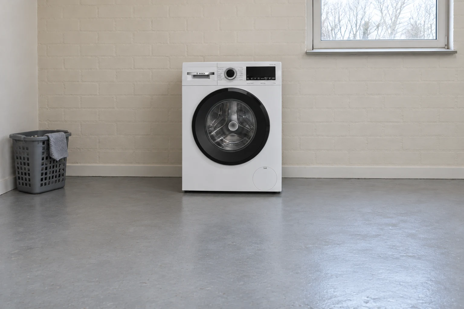 Bosch-wasmachine in een eenvoudige wasruimte met een doek over de wasmand.