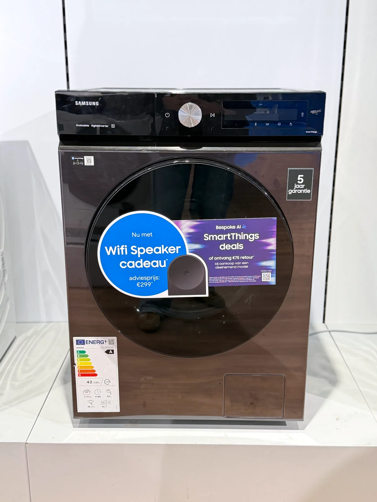 Samsung WW11DB7B34GBU3 in een winkelopstelling met gesloten deur en energielabel